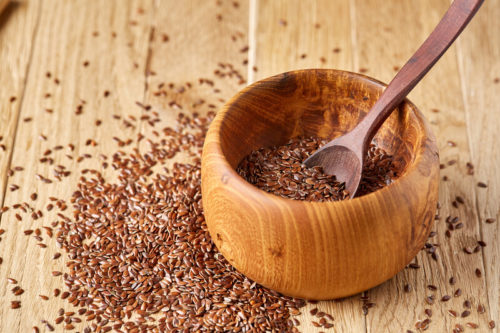 wooden bowl with spoon filled with seeds on wooden table